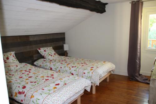 two beds sitting in a room with a window at Moulin des Faurilloux in La Chapelle-Faucher
