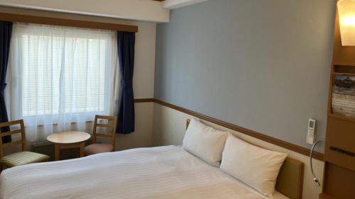 a hotel room with a bed and a window at Toyoko Inn Niigata Furumachi in Niigata