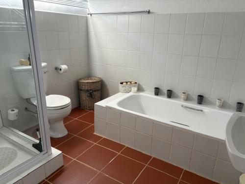 a bathroom with a white tub and a toilet at Silver Linings Cottage in Parys