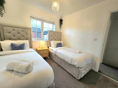 a bedroom with two beds and a chandelier at The Charm Luxury House - 8mins to NEC, Birmingham Airport in Marston Green