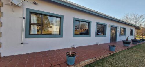 a white house with windows and potted plants on a brick patio at Riverside Farm in eMalahleni
