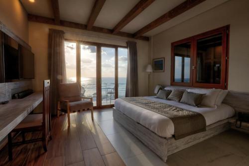 ein Schlafzimmer mit einem Bett und Meerblick in der Unterkunft El Boutique Hotel in Tyros