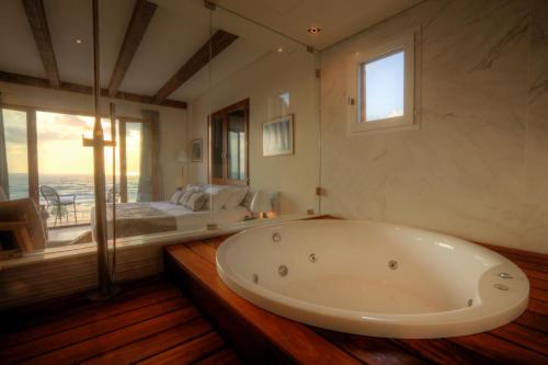 eine große Badewanne in einem Zimmer mit einem Bett in der Unterkunft El Boutique Hotel in Tyros