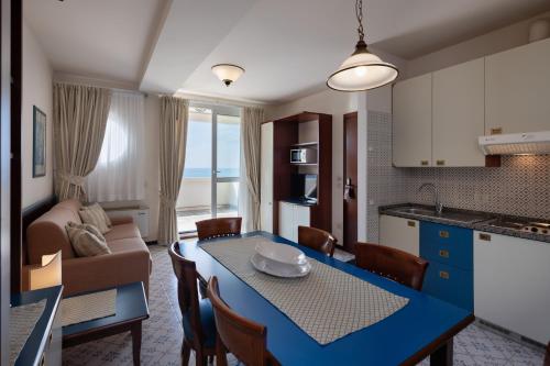 a kitchen and living room with a blue table and chairs at Aparthotel Holiday in Bibione