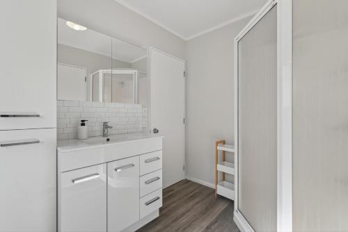 a white bathroom with a sink and a mirror at Welcome Bay Stay in Tauranga