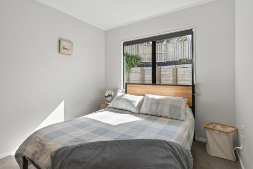 a bedroom with a bed and a large window at Welcome Bay Stay in Tauranga