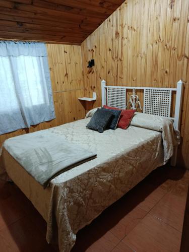a bedroom with a bed in a room with wooden walls at EL LOTE DE VERO in Las Compuertas