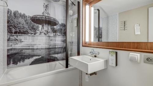 a bathroom with a sink and a bath tub at Campanile NATURE - Vierzon in Vierzon
