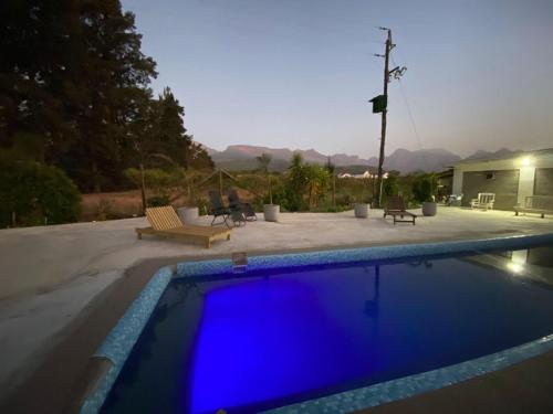 a swimming pool with blue water in front of a house at Magents Farm Guesthouse in Paarl