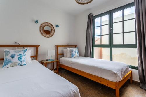 two beds in a room with a window at Casa Lili - Shared Pool - Close to Seafront Promenade - Sea Views from upper terrace in Punta Mujeres