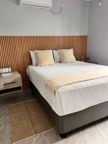 a bedroom with a large bed with a wooden headboard at Marble Crest Guest House in Maun