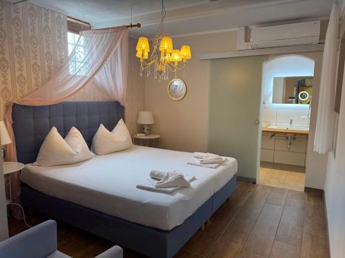 a bedroom with a large bed with a chandelier at Pension Amelie in Mörbisch am See