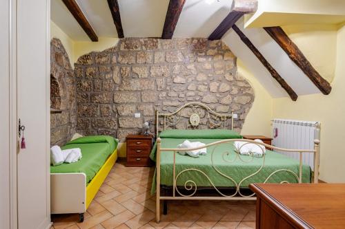 a bedroom with two beds and a stone wall at The Stone House Historic Center in Grotte di Castro