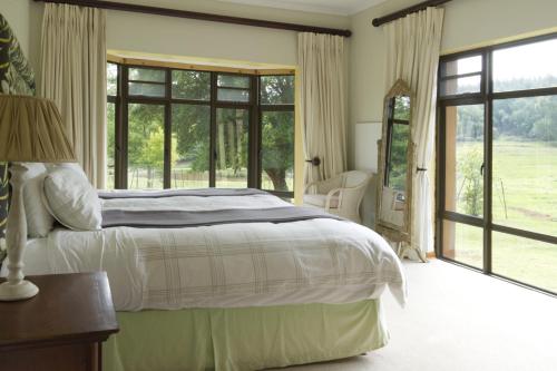 a bedroom with a bed and a large window at Elgin Farm Dullstroom in Dullstroom