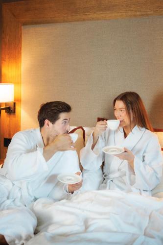 a man and a woman sitting in bed drinking coffee at Vestlia Resort in Geilo