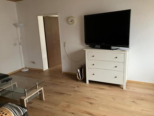 a living room with a flat screen tv on a dresser at Ferienwohnung Forstwiese in Großrosseln