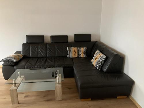 a black leather couch in a living room with a table at Ferienwohnung Forstwiese in Großrosseln