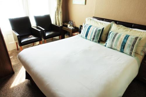 a large white bed with two chairs in a room at Oakover Guest House in Weston-super-Mare