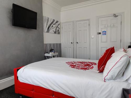 a bedroom with a large white bed with red pillows at Oakover Guest House in Weston-super-Mare