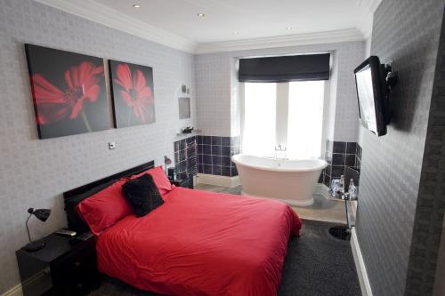 a bedroom with a red bed and a bath tub at Oakover Guest House in Weston-super-Mare