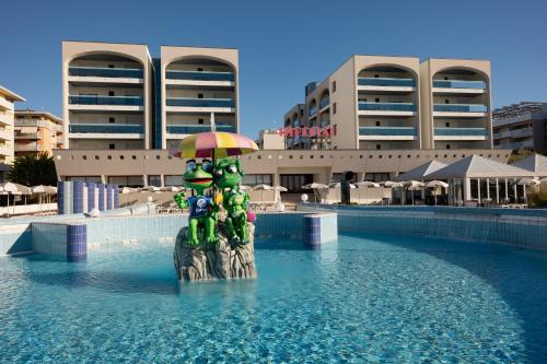a statue in a pool with an umbrella in the water at Aparthotel Imperial in Bibione