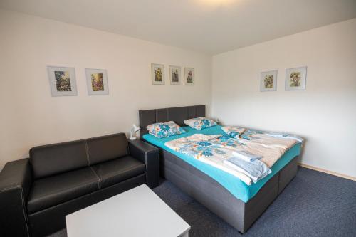a bedroom with a bed and a leather couch at Apartmán Absolon Blansko in Blansko