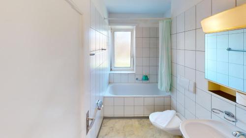 a bathroom with a tub and a toilet and a sink at Functional Stay with Balcony in Zurich