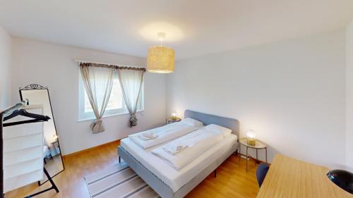 a white bedroom with a bed and a table at Functional Stay with Balcony in Zurich