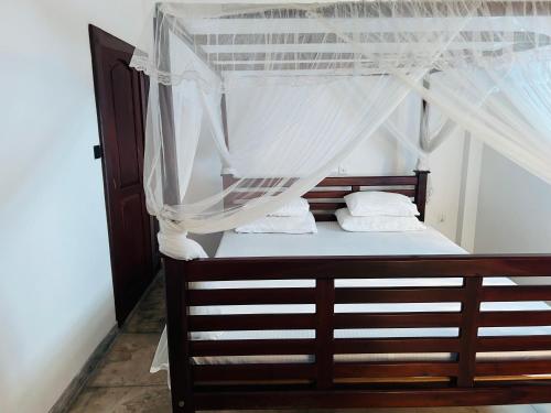 a bedroom with a canopy bed with white sheets and pillows at Hikka Residence 98 in Hikkaduwa