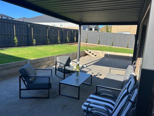 a patio with lounge chairs and a table and a fence at Coastal Oasis - 10 mins to Torquay, 10 mins to Geelong ! in Mount Duneed