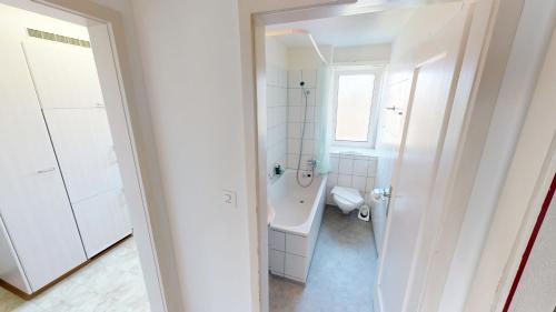 a white bathroom with a tub and a toilet at Practical Apartment Near Seebach in Zurich