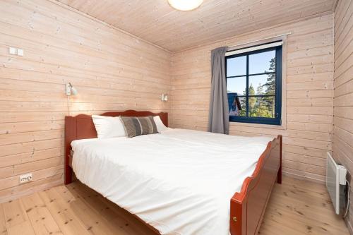 a large bed in a wooden room with a window at Marits Hytte 6p in Vradal