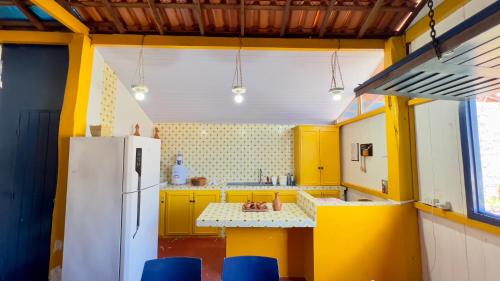 a kitchen with yellow cabinets and a white refrigerator at Casa da Barra Tutóia in Tutóia