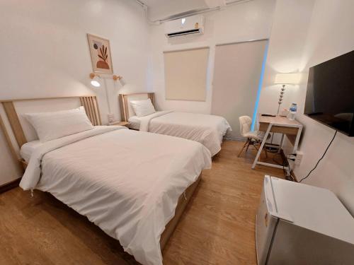 a hotel room with two beds and a television at Vevey Mansion in Bangkok