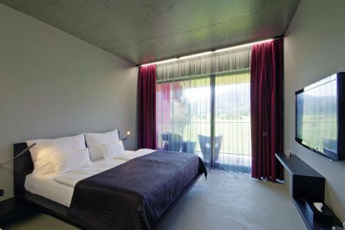 a bedroom with a bed and a tv and a window at Miura Hotel in Čeladná