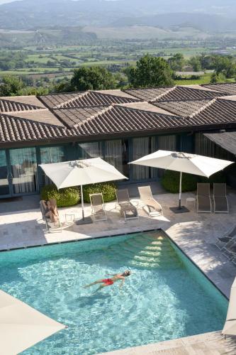 a person swimming in a swimming pool with umbrellas at Altarocca Wine Resort Adults Only in Orvieto