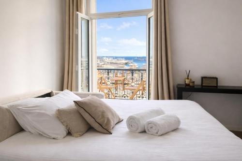 a bedroom with a large window and a bed with towels at DELUXE SEAVIEW BALCONY - 2 min PALAIS & BEACH in Cannes