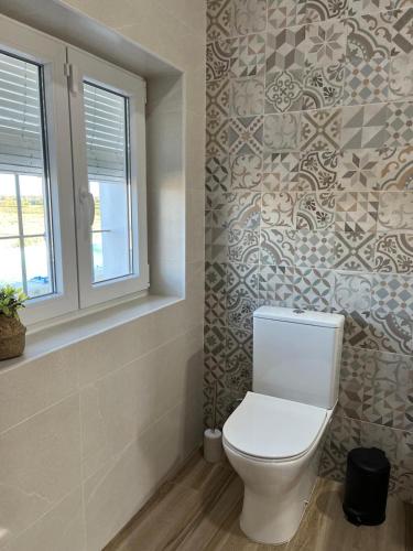 a bathroom with a toilet and a window and tiles at Los Granainos in Arcos de la Frontera
