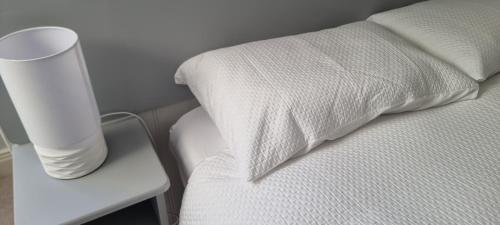 a white bed with a pillow and a vase on a side table at This is the Place in Ballinrobe