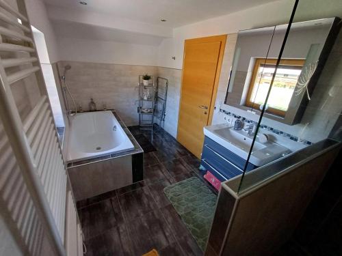 a bathroom with a tub and a sink and a mirror at Ferienwohnung Bergtroll in Uderns