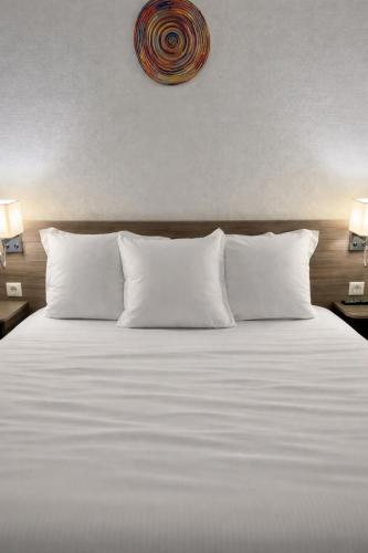 a bed with white sheets and pillows in a room at Contact Hôtel Marseille Aubagne in La Penne-sur-Huveaune
