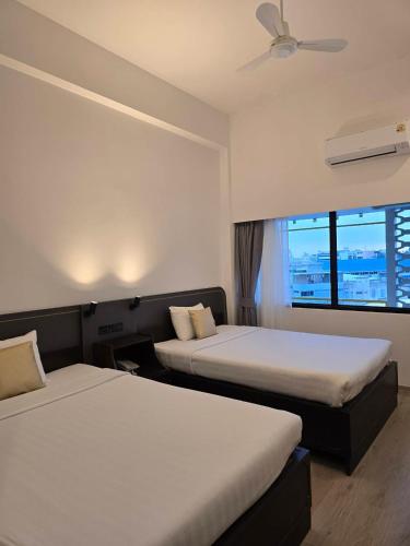 a hotel room with two beds and a window at The Krungkasem Srikrung Hotel in Bangkok