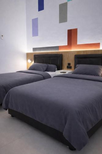 two large beds in a bedroom with a wall at De Azka Style Syariah in Malang