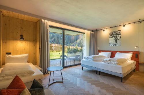 a bedroom with two beds and a large window at La Tambra - Hotel Lodge in Santa Cristina Gherdëina
