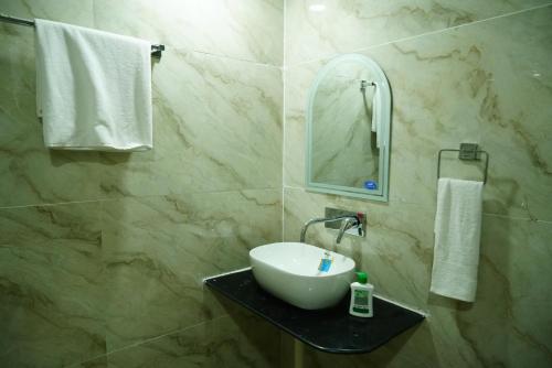 a bathroom with a sink and a mirror at Badrika Farm's in Rewa