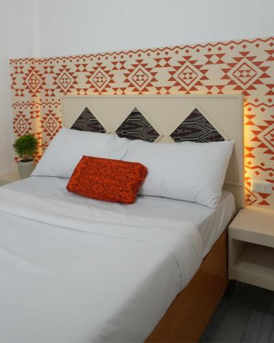 a bedroom with a white bed with a red pillow at Bila Boutique Hotel in Lagao II