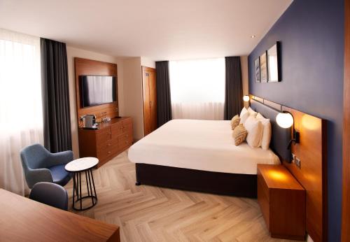 a hotel room with a bed and a chair at Thistle London Hyde Park Kensington Gardens in London