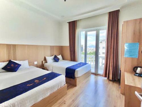 a hotel room with two beds and a balcony at Huy Đạt Hotel in Phan Thiet