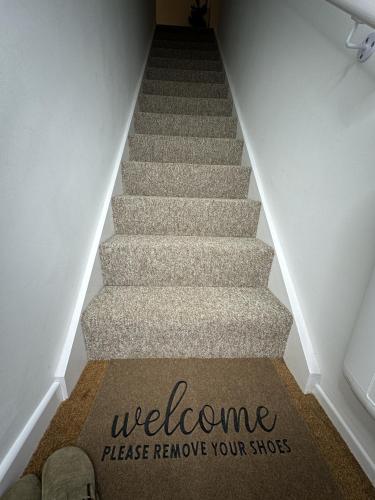 a welcome rug on the stairs with the words welcome please remove your shoes at Rosern Short Stays in St. Ives