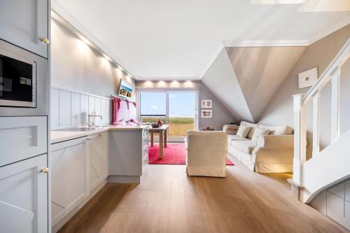 a kitchen with white cabinets and a living room at Fernsicht in Morsum